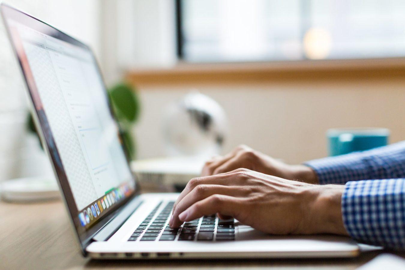 Close up of a laptop with two hands using the keyboard